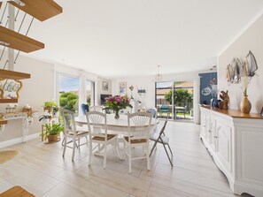 A spacious dining area with white furniture, a large window, and a view of the outdoors. - House with garden, 7 adults 1 child (Saint-Michel-Chef-Chef)