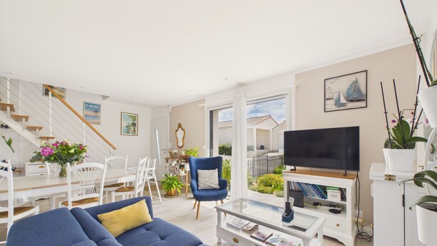 A living room with a sofa, a television, a dining area with chairs, and a staircase. - House with garden, 7 adults 1 child (Saint-Michel-Chef-Chef)