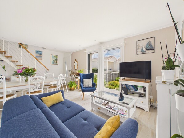 A living room with a sofa, a television, a dining area with chairs, and a staircase. - House with garden, 7 adults 1 child (Saint-Michel-Chef-Chef)