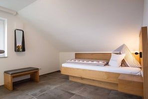 Ein kleiner, gemütlicher Raum mit einem Bett, einer Bank und einem Spiegel an der Wand.