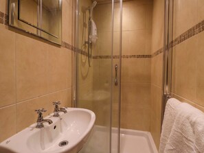 A bathroom with a glass-enclosed shower, a white sink with a single faucet, and a white towel hanging on the wall. - Blacksmiths Retreat (York)