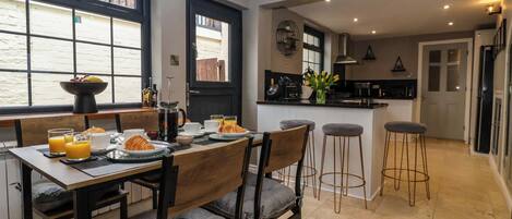Una cocina moderna con comedor, que incluye un desayuno con cruasanes, café y fruta.