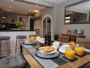 A breakfast setup with croissants, orange juice, and coffee on a table with a view of the kitchen and dining area. - Blacksmiths Retreat (York)