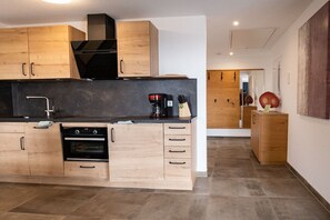 Una cocina moderna con armarios de madera, encimera negra y horno empotrado.