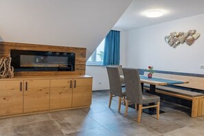 Una cocina moderna con horno integrado, armarios de madera y un comedor con banco y sillas.