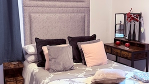 A bedroom with a bed, pillows, a bedside table, a mirror, and a painting on the wall. - Apartment Sleeps 2 With Parking (Aberdeen)