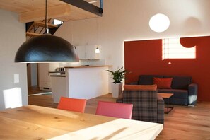 Ein modernes Interieur mit Essbereich, einer Couch und einer Küche im Hintergrund.