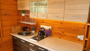 A compact kitchen with wooden cabinetry, a sink, a kettle, and a small countertop area. - Cottages for 4 People With a Swimming Pool (Kamien Pomorski)