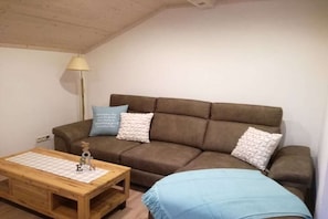 Ein gemütliches Wohnzimmer mit einem braunen Sofa, einem Holztisch und einer Lampe.