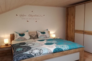 Ein Schlafzimmer mit Bett, Kissen, einer Wand mit Text und einem hölzernen Kopfteil.