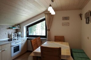 Eine kleine Küche mit Fenster, Holzbalkendecke und einfachen Möbeln.