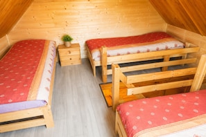 A small, wooden room with two beds, a nightstand, and a potted plant. - Cottages With a Pool for 5 People (Kamien Pomorski)