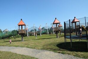 A playground with multiple play structures, including a climbing net and a trampoline. - Cottages With a Pool for 5 People (Kamien Pomorski)