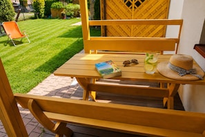 A wooden outdoor table with a book, sunglasses, and a drink on it. - Cottages With a Pool for 5 People (Kamien Pomorski)