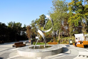A public park with a modern sculpture, benches, and trees. - Cottages With a Pool for 5 People (Kamien Pomorski)