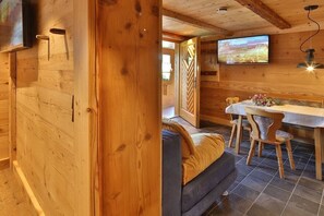 Et interiør i træ med en seng, et spisebord med stole og et fjernsyn monteret på væggen.