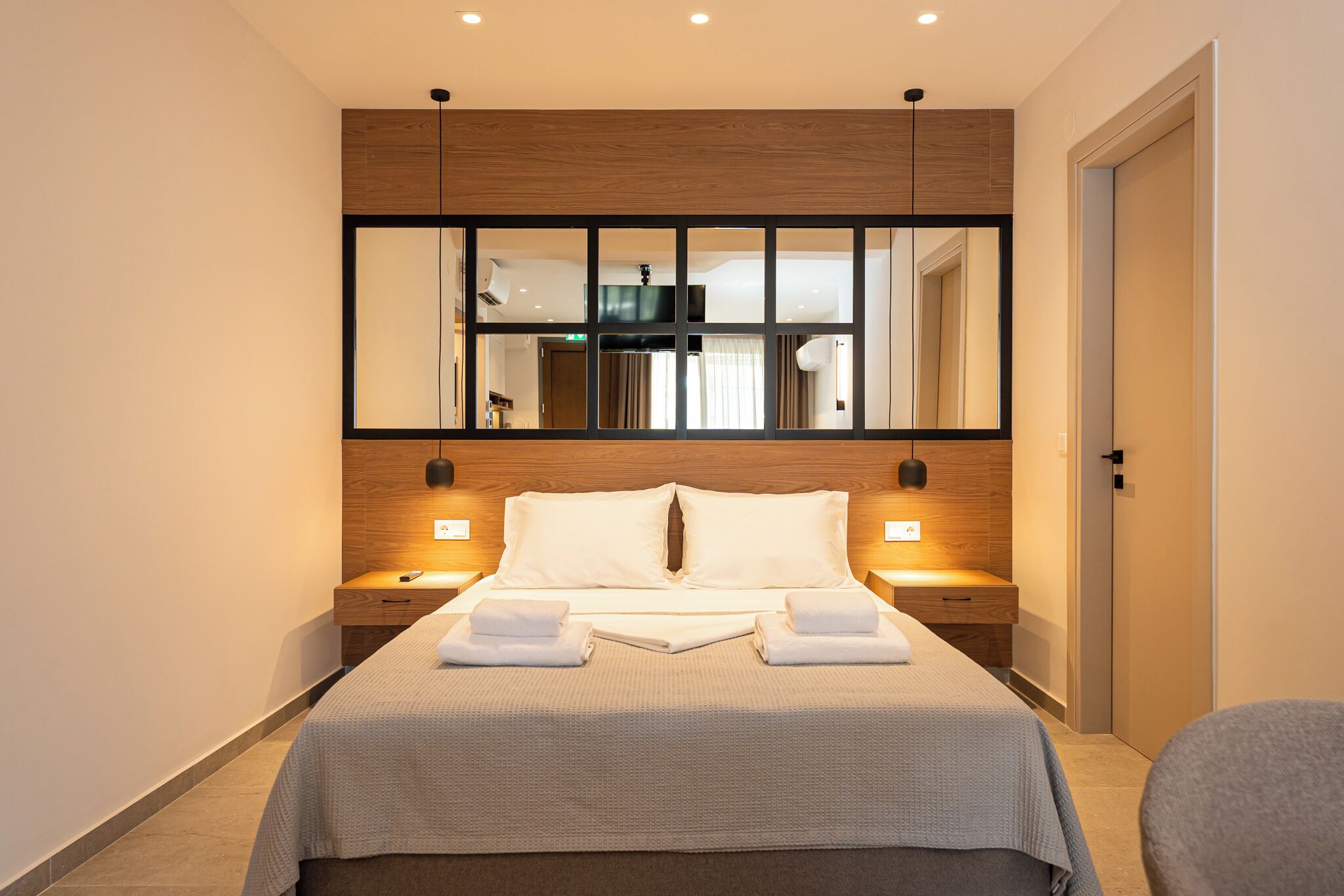 A hotel room with a large bed, bedside lamps, a mirror, and a view of the bathroom.