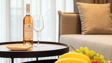 A bottle of Bibaia XO wine, a glass, and a fruit basket on a round table in a room with a sofa and curtains.