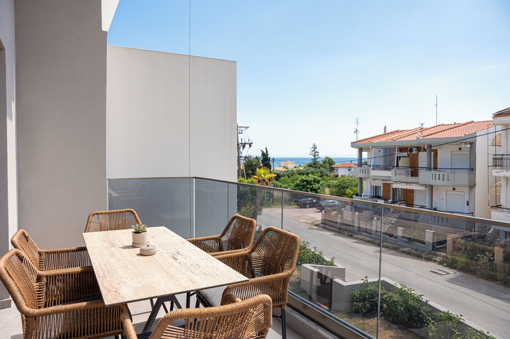 Ein Balkon mit Korbmöbeln, Blick auf die Straße und ein Gebäude mit Ziegeldach.