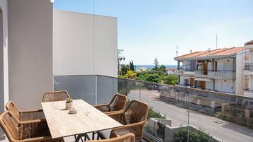 Ein Balkon mit Korbmöbeln, Blick auf die Straße und ein Gebäude mit Ziegeldach.