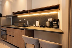 A modern kitchen with built-in appliances, a coffee maker, and a kettle on the countertop. - Sea Breeze Luxury Apartments (Nea Propontida)