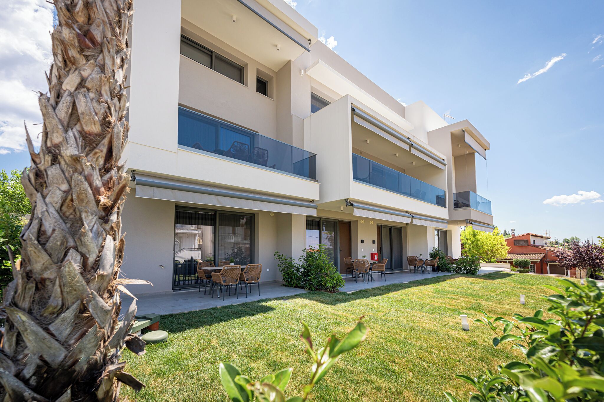 A modern two-story building with balconies, a well-maintained lawn, and outdoor seating.