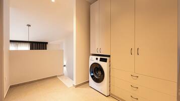 A laundry room with a washing machine, cabinets, and a ceiling light.