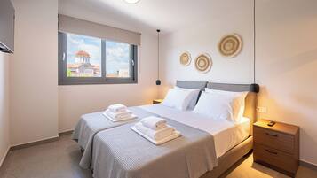 A hotel room with a bed, two bedside tables, a window with a view of a building, and decorative wall art.