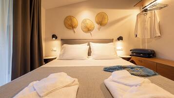 A hotel room with a bed, two bedside tables, a wall-mounted lamp, a suitcase, and a towel rack.