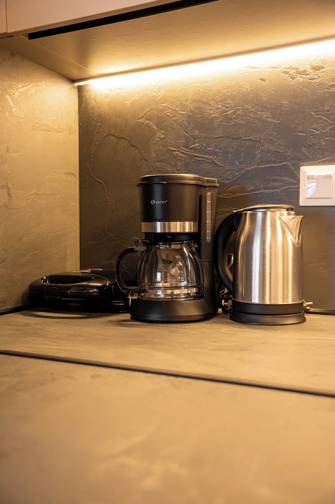 Een koffiezetapparaat en een waterkoker op een aanrecht.