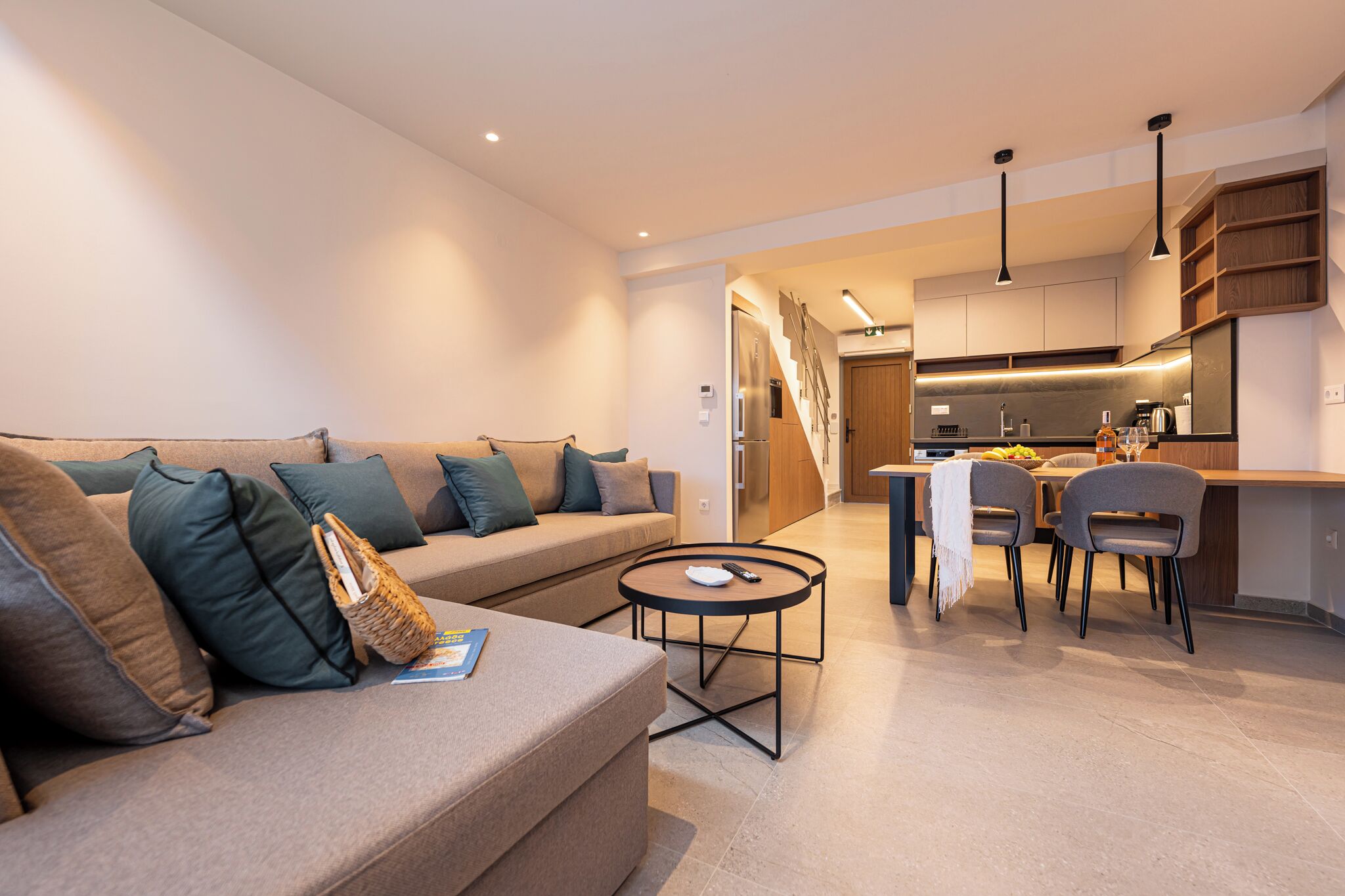Un salon moderne comprenant un canapé, une petite table ronde et un coin cuisine avec une table à manger et des chaises.