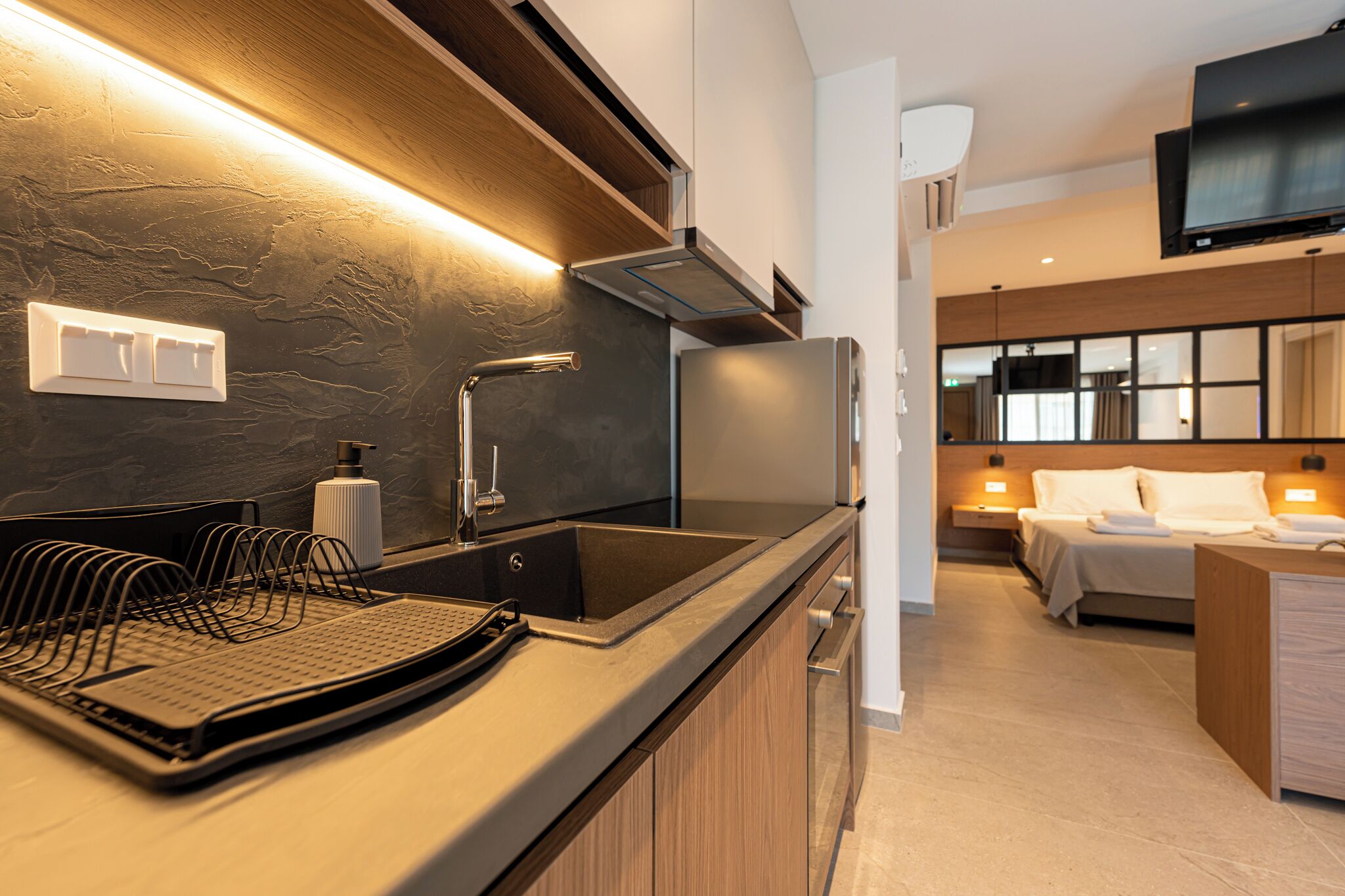 Una cocina moderna con horno integrado, un lavamanos y una encimera con un escurreplatos.