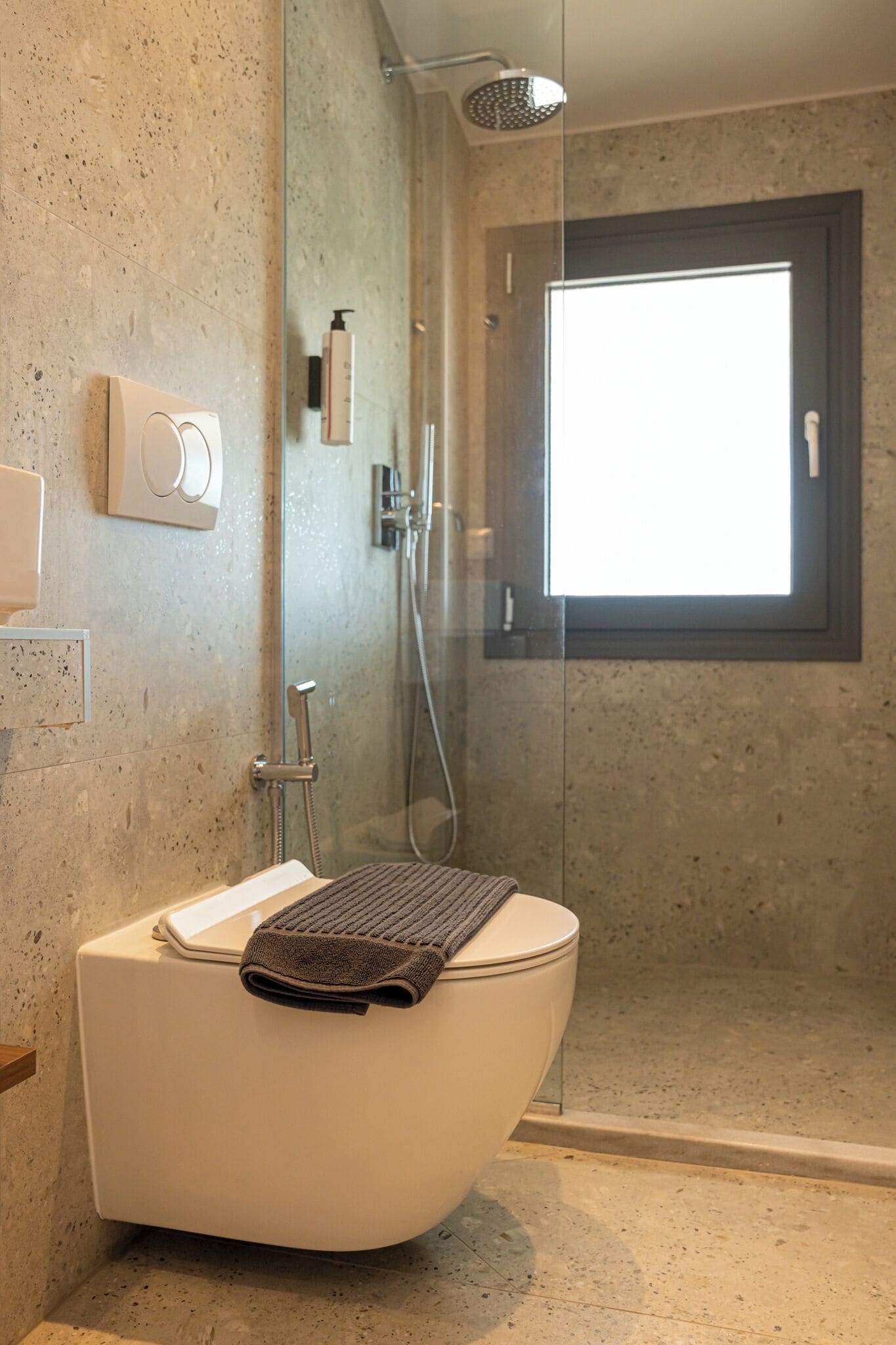 Een moderne badkamer met een vrijstaand bad, een douche met glazen wand en een raam voor natuurlijk licht.