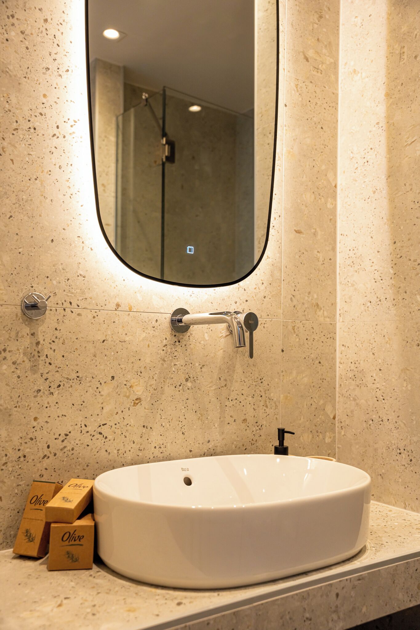 Un baño con lavamanos blanco, espejo y ducha.