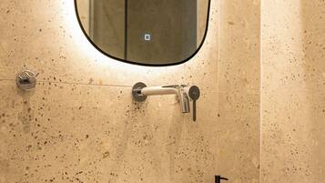 Un baño con lavamanos blanco, espejo y ducha.