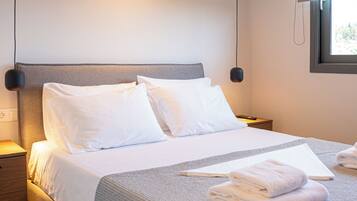 A modern hotel room with a large bed, bedside tables, and a window with a view.