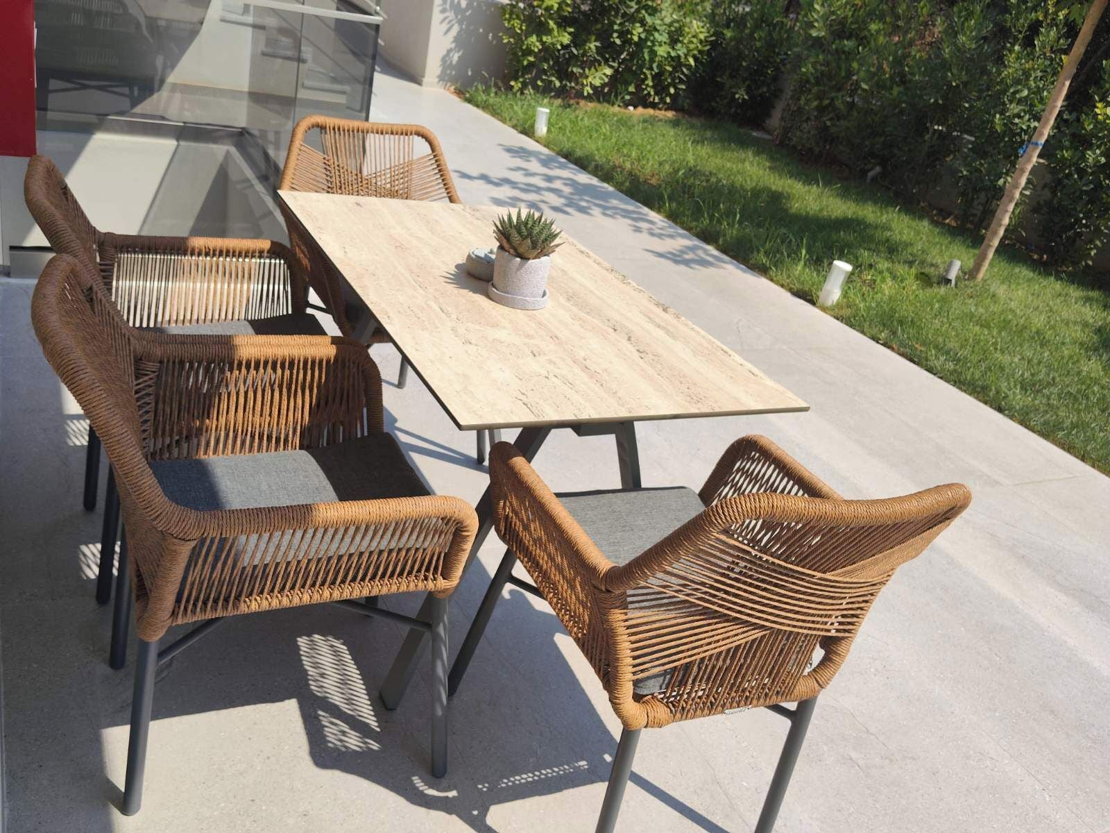 An outdoor dining area with a wooden table and wicker chairs.