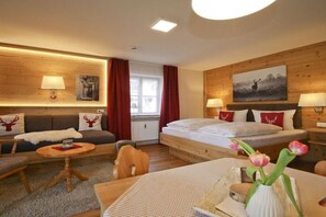 Ein gemütliches Zimmer mit einer Couch, einem Bett, einem kleinen Tisch und einer Lampe.