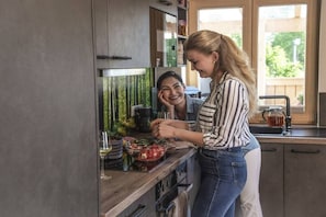 A kitchen with a modern design, featuring a stainless steel refrigerator, a wooden countertop, and a window providing natural light.