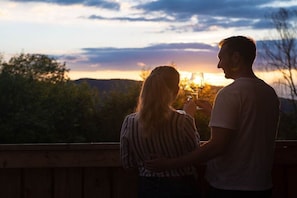 Ein Paar steht auf einem Balkon mit Blick auf den Sonnenuntergang.