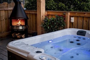 A hot tub with jets, a wood-burning stove, and a wooden deck.