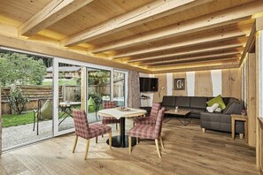 A wooden interior with a dining area, sofa, and a TV.