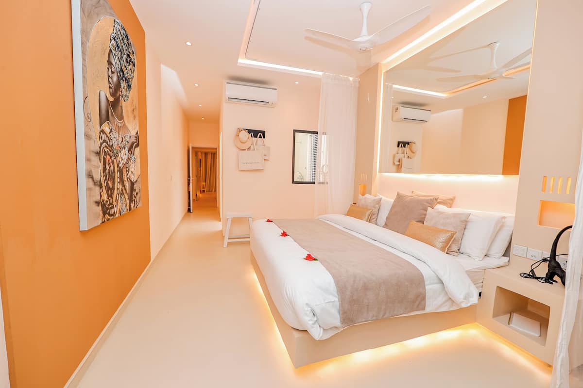 A modern hotel room with a large bed, bedside tables, a ceiling fan, and an air conditioning unit.