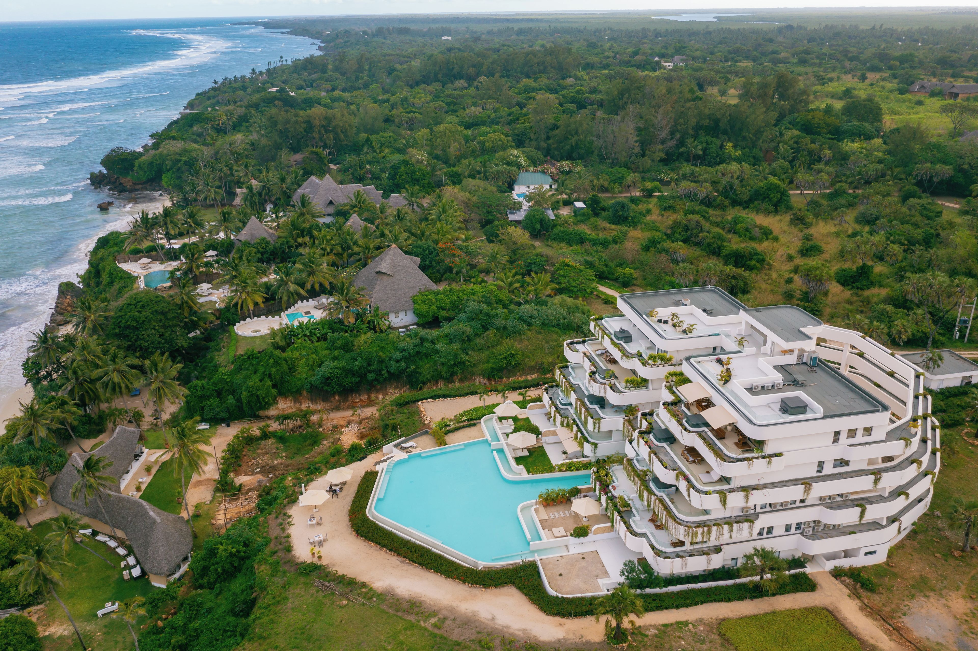 Een resort met een zwembad, meerdere gebouwen en een strand.