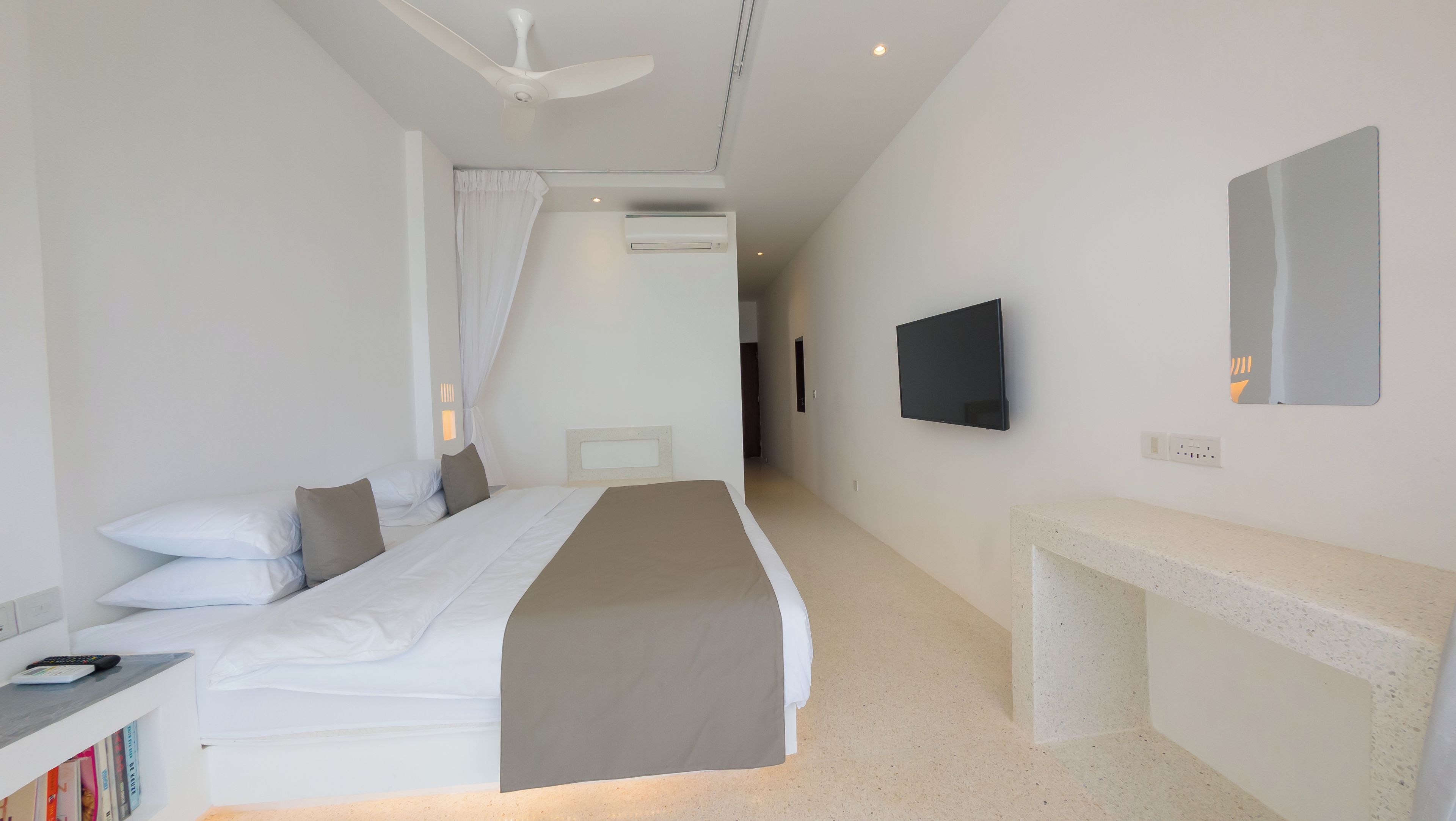 Een hotelkamer met een bed, nachtkastje, televisie en een spiegel.