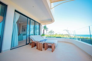 A balcony with a bed, a table, and a chair, overlooking the ocean. - One Ocean Apartments  by Nest&Nomad (Msambweni)