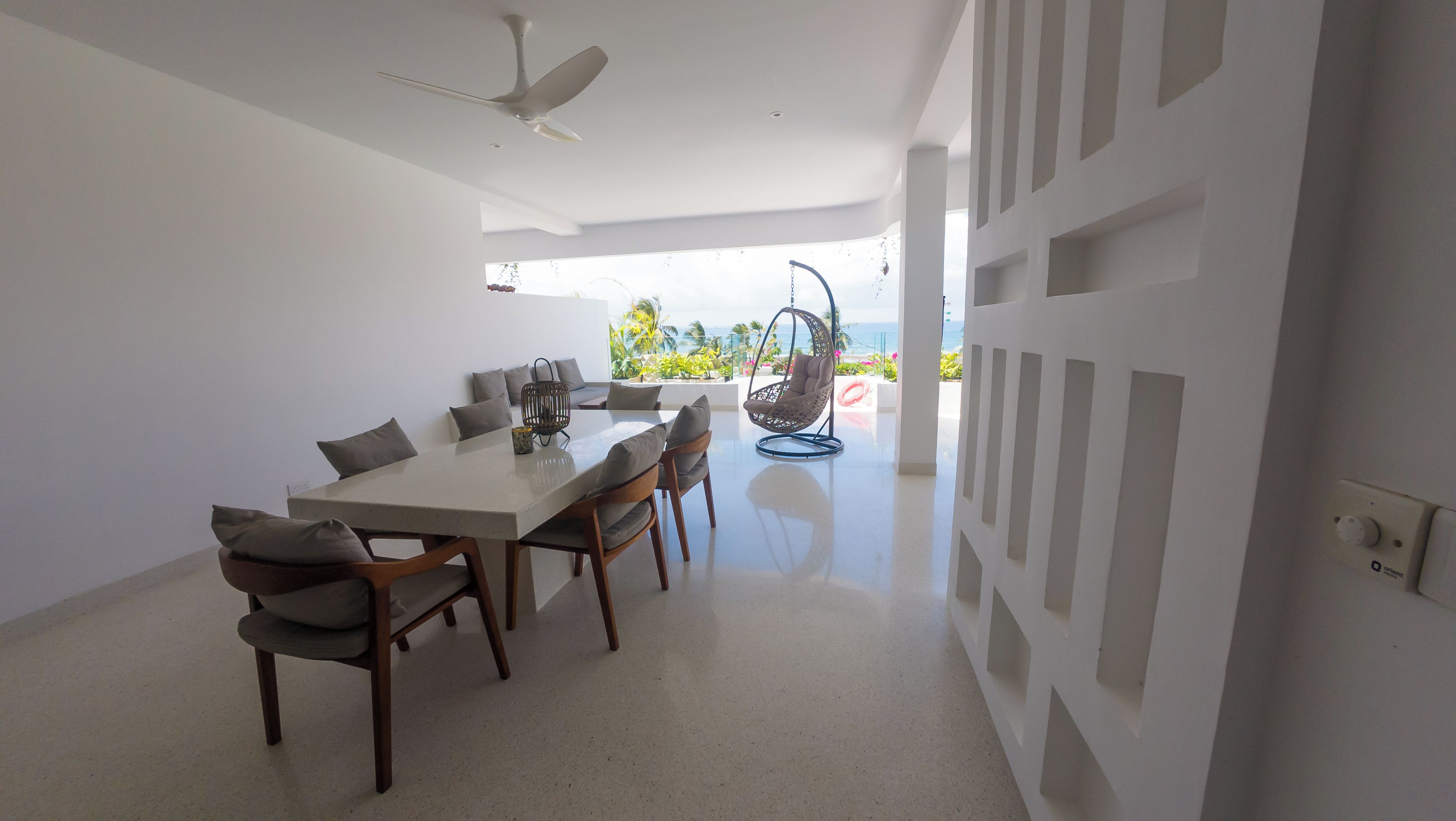 A modern dining area with a table, chairs, and a hanging chair.