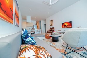 A modern living room with a sofa, a chair, a coffee table, and artwork on the walls.
