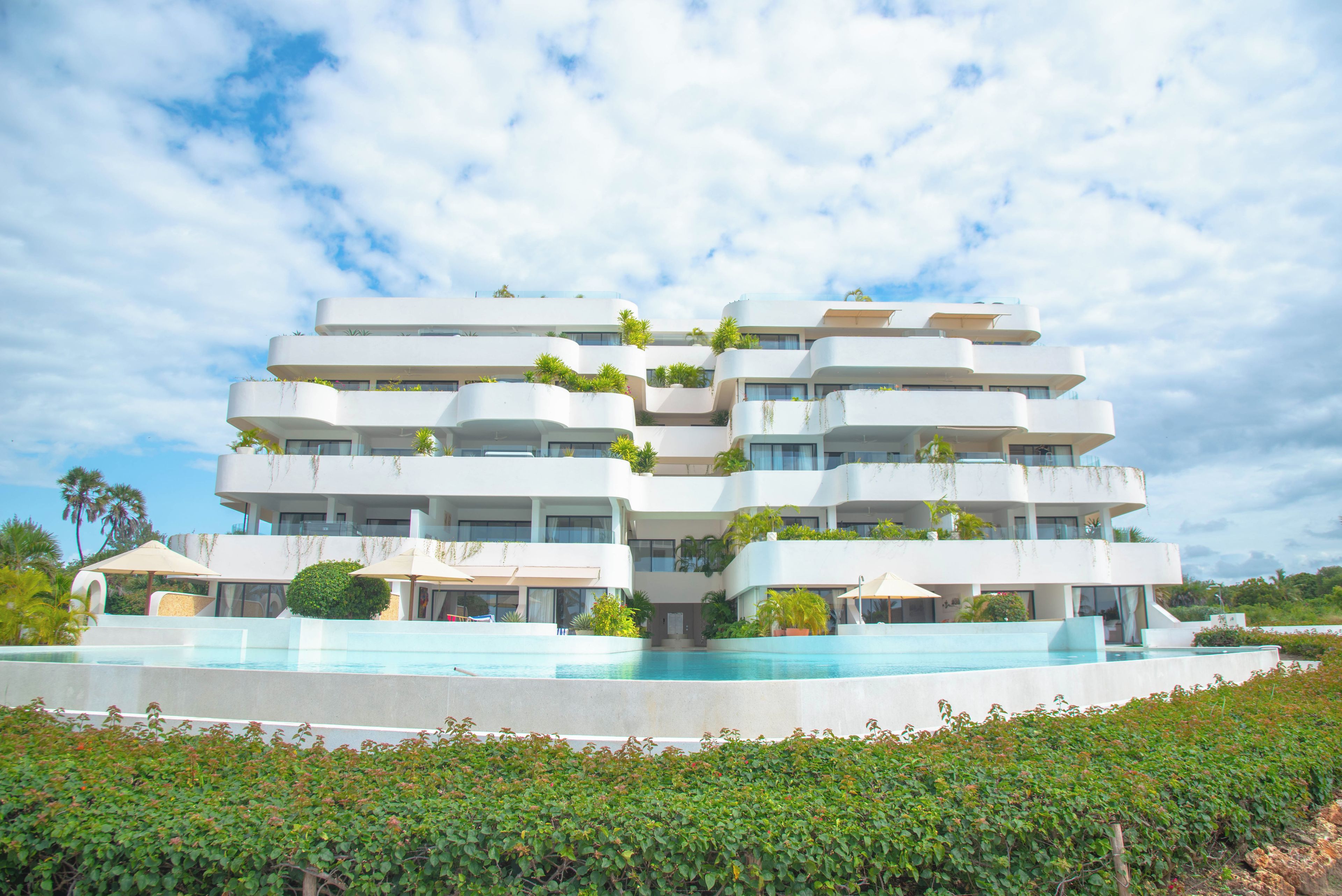 Un hotel de varios pisos con una piscina al frente.