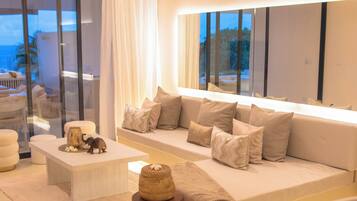 Una sala de estar moderna con un sofá grande, una mesa de centro y un taburete de madera decorativo.